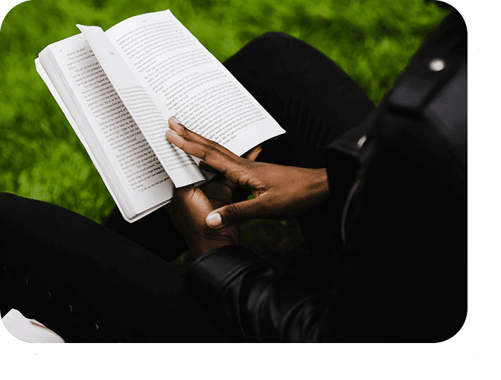 A person sitting on the ground reading a book.