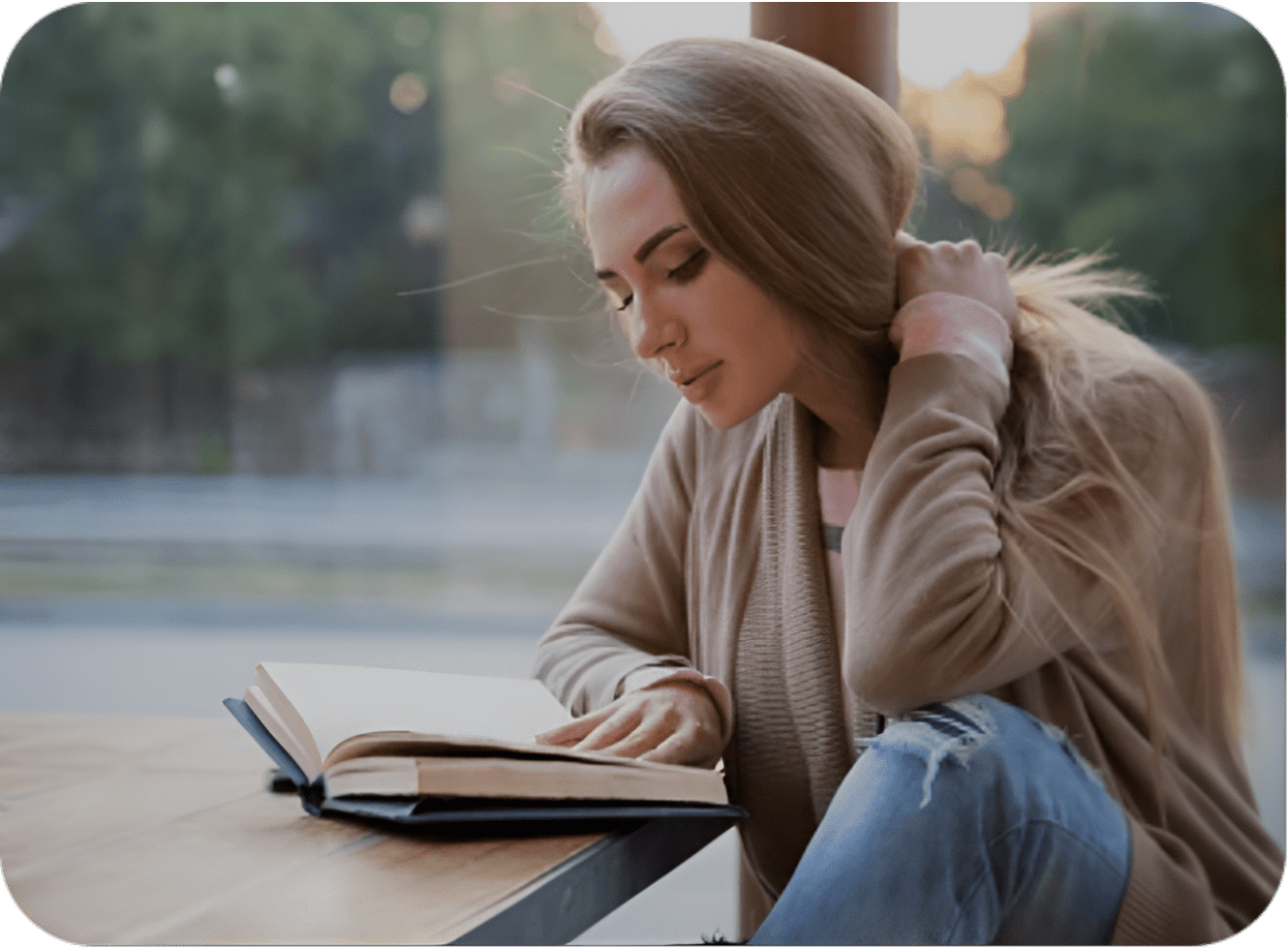 A woman sitting on the ground reading a book.
